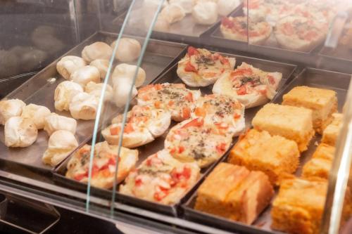 a display case with a bunch of pizzas and bread at Astor Hotel in Bauru