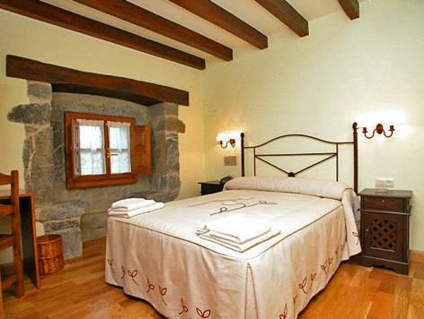 a bedroom with a bed and a stone wall at La Casona De Baró in Baró