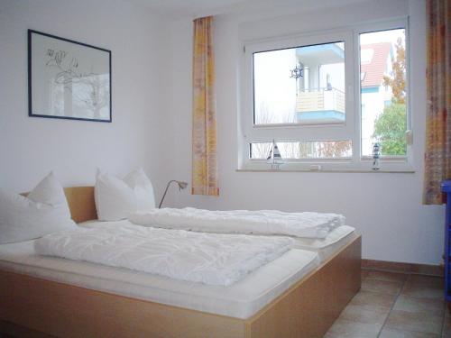 een slaapkamer met een bed met witte lakens en een raam bij Fewo Strandrevier in Zingst