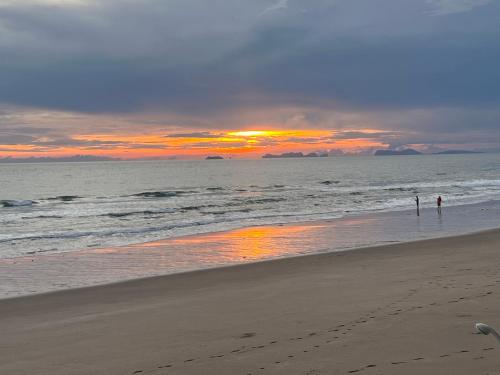 Lanta Seafront Resort في كو لانتا: شخصين واقفين على الشاطئ عند غروب الشمس