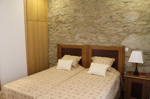 a bedroom with a bed and a stone wall at Quinta Anna Horvath in Vale de Cambra