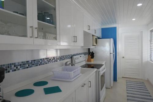 a kitchen with white cabinets and a white refrigerator at Zenbreak Freshwater Beachfront 6 in Saint Michael