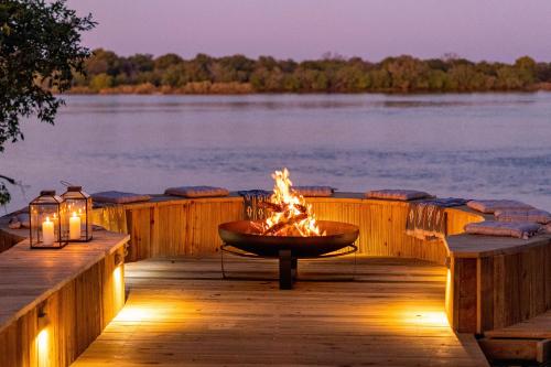 a fire pit on a dock next to a body of water at Victoria Falls River Lodge in Victoria Falls
