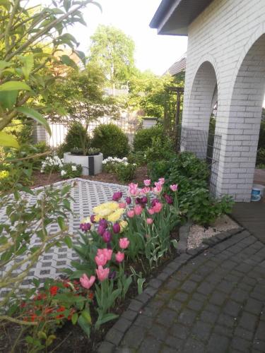 einen Garten mit rosa und gelben Blumen auf einem Backsteinsteg in der Unterkunft Boarding-Haus, Ostercappeln in Ostercappeln