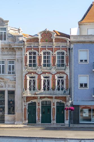 a large building with green doors on a street at Sleep in Centre - Aveiro in Aveiro