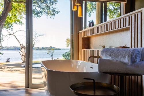 a bath tub in a bathroom with a view of the water at Victoria Falls River Lodge in Victoria Falls
