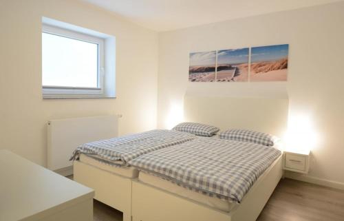 ein weißes Schlafzimmer mit einem Bett und einem Fenster in der Unterkunft Haus Katharina links in Wyk auf Föhr