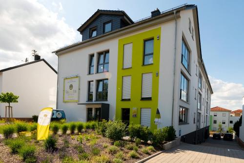 a yellow and white building with a sign in front of it at Vis Saar Vie - Ferienwohnungen an der Saarschleife in Mettlach