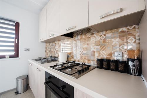 a kitchen with white cabinets and a stove top oven at Venite apartments in Velika