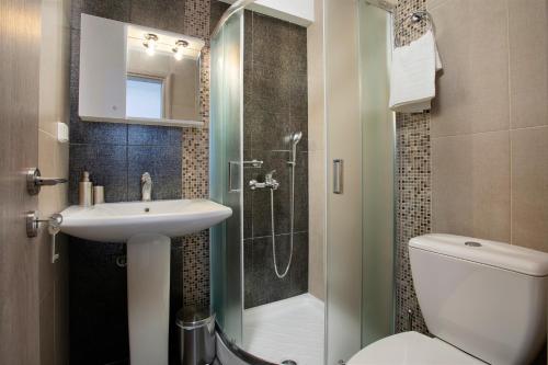 a bathroom with a shower and a sink and a toilet at Serenity Villa in Kórinthos