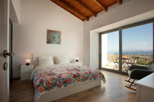 a white bedroom with a bed and a large window at Serenity Villa in Kórinthos