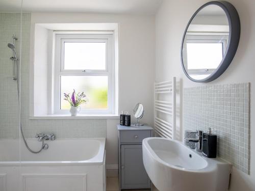 uma casa de banho branca com um lavatório e um espelho em Kimkeri em Bourton on the Water