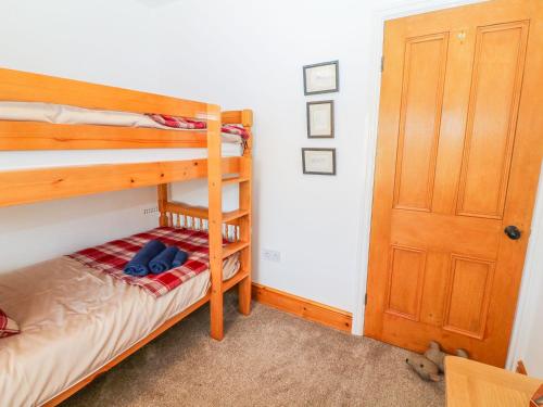 a bedroom with two bunk beds and a door at Morannedd in Llanfairpwllgwyngyll
