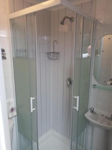 a shower with a glass door next to a sink at Strides Hotel in Blackpool