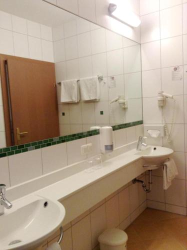 uma casa de banho com 2 lavatórios e um espelho grande em 1A Landhotel Schicklberg em Kremsmünster