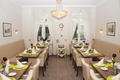 un ristorante con tavoli lunghi, sedie e lampadario a braccio di Hotel Haus Berlin a Bonn