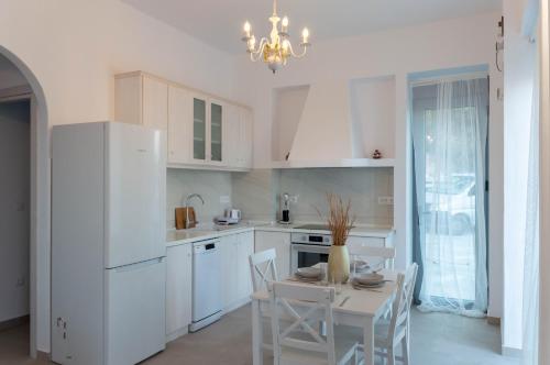 a kitchen with white cabinets and a table and chairs at Villa Iliousa Grand in Psinthos