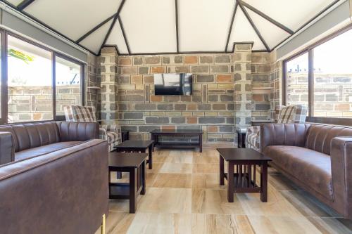 a waiting room with leather couches and a tv on a brick wall at Rock Hyrax Hotel in Nakuru