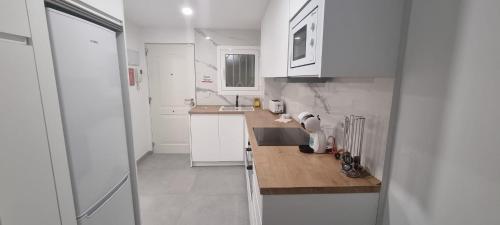 a kitchen with white cabinets and a wooden counter top at Principado Benidorm Suites Levante in Benidorm