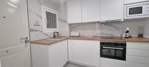 a white kitchen with a sink and a microwave at Principado Benidorm Suites Levante in Benidorm