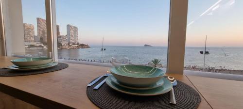 a table with two bowls and a view of the ocean at Principado Benidorm Suites Levante in Benidorm