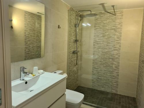 uma casa de banho com um WC, um lavatório e um chuveiro em Appartement avec cuisine et grande piscine chauffée em Hendaye