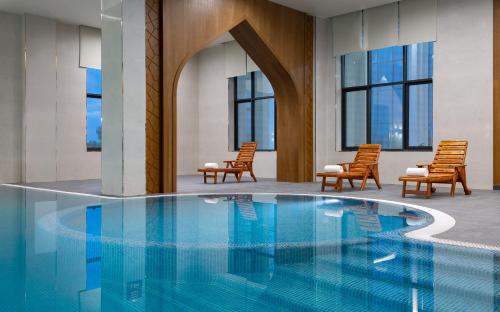 a hotel lobby with a pool with chairs and windows at Farovon Khiva Hotel in Khiva
