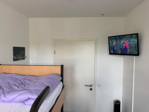 a bedroom with a bed and a tv on the wall at FeWo Hostel in Cologne