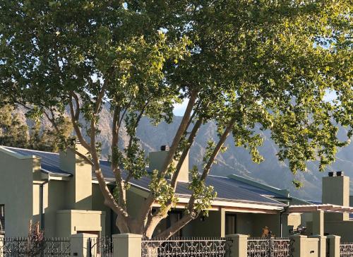a house with trees and mountains in the background at Jardin de la Ferme in Franschhoek