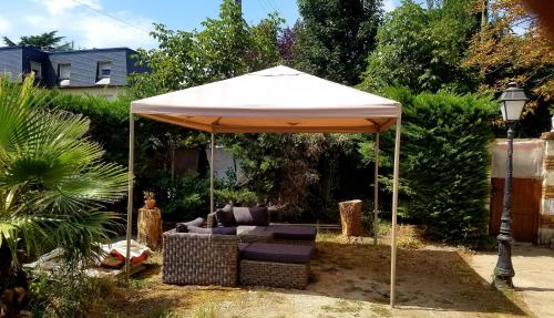 a white umbrella with a couch under it in a yard at Normandy cottage in Gagny