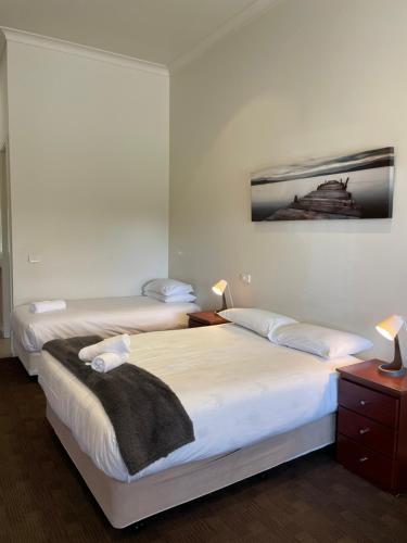 two beds in a bedroom with two lamps and a picture on the wall at Falcon Hotel Motel in Kanyapella