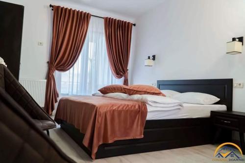 a bedroom with a bed with orange sheets and a window at Conacul Doamnei in Corbi