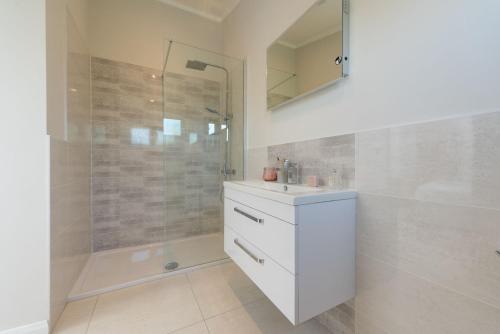 a bathroom with a white sink and a shower at Orchid Lodge, 23 Roadford Lake Lodges in Lifton