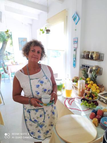 a woman standing in a kitchen holding a cup at B&B Volver in Peschici