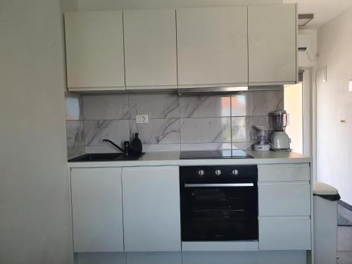 a kitchen with white cabinets and a black oven at Studio apartment Laura || in Murter