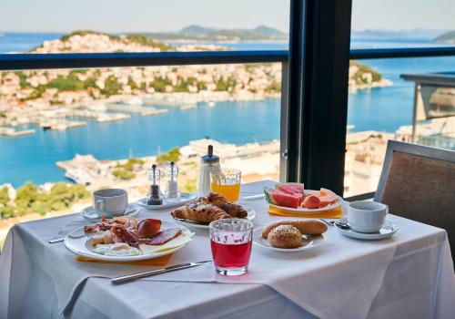 a table with plates of food and a view of the ocean at Hotel Adria in Dubrovnik