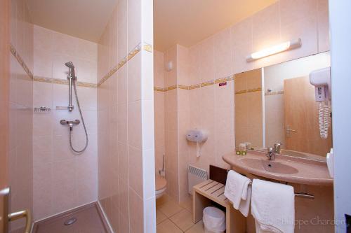 een badkamer met een wastafel, een douche en een toilet bij Logis Jum'Hotel in Saints-Geosmes