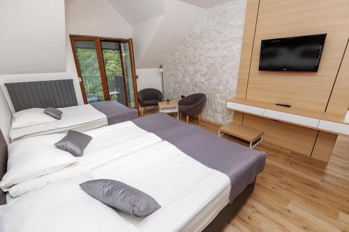 a bedroom with two beds and a flat screen tv at Gostilna Müller in Črnomelj