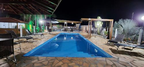 a large swimming pool with chairs and a table at Pousada Lago Azul in Delfinópolis