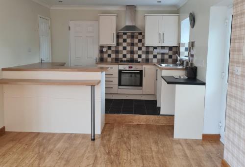 a kitchen with white cabinets and a stove top oven at Richlands Homestay in Tondu