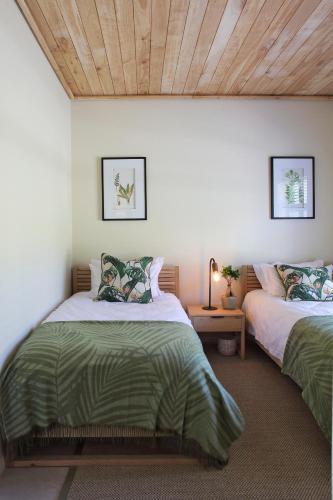 a bedroom with two beds and a wooden ceiling at Jardin de la Ferme in Franschhoek