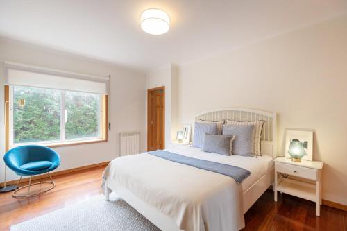 a bedroom with a large bed and a blue chair at São Félix Seaside Oasis in São Félix da Marinha