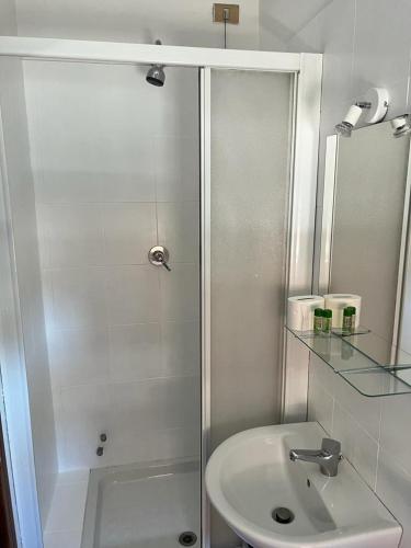 a white bathroom with a shower and a sink at Ubika Hotel in Porto San Giorgio