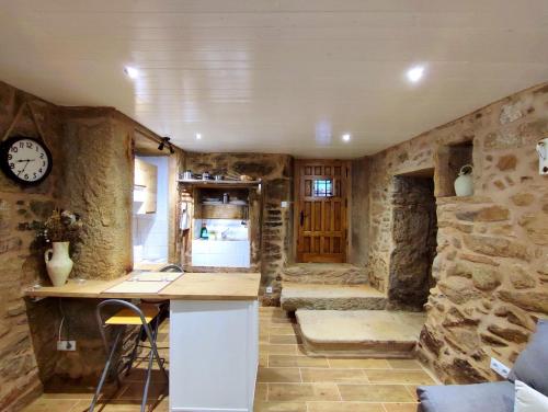 a kitchen with stone walls and a counter with a clock at A Cuadriña in Mazaricos