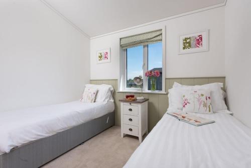 une chambre avec deux lits et une fenêtre dans l'établissement Periwinkle Lodge, 3 Roadford Lake Lodges, à Lifton