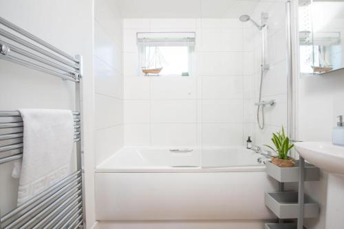 une salle de bain blanche avec une baignoire et un lavabo dans l'établissement Periwinkle Lodge, 3 Roadford Lake Lodges, à Lifton