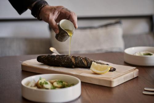 a person is pouring lemon juice on a piece of food at Archipelagos All Suites in Elia Beach
