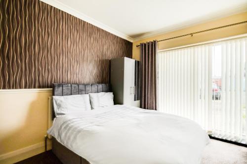 a bedroom with a white bed and a window at OYO The Longlands Hotel in Middlesbrough