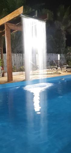 a swimming pool with a waterfall in the background at Pousada Lago Azul in Delfinópolis