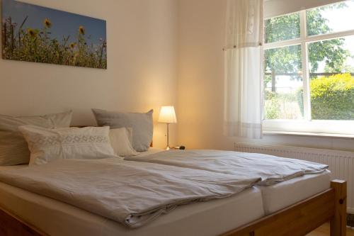 Cama blanca en habitación con ventana en Hof Timmermann - Pferdestall, en Ottenstein